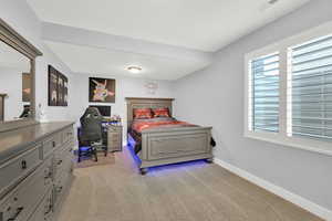 Bedroom featuring multiple windows, light colored carpet and baseboards