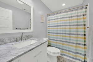 Full bathroom with toilet, vanity, recessed lighting, and a shower with shower curtain