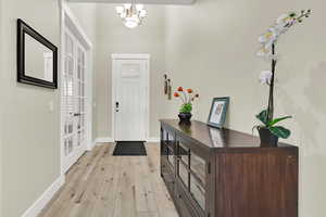 Entryway featuring a chandelier, light wood-type flooring, baseboards, and french doors