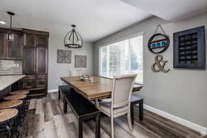 Dining space with baseboards, dark wood-style floors, and a chandelier