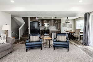 Living area with light wood-style floors, stairs, and recessed lighting