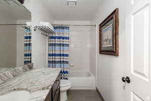 Full bath featuring vanity, shower / tub combo with curtain, tile patterned flooring, toilet, and baseboards