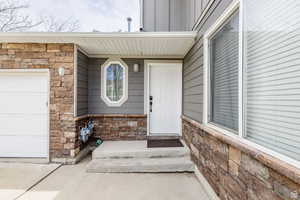 Property entrance featuring stone siding, a garage, and board and batten siding