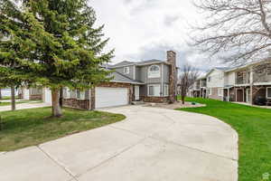 Traditional home with concrete driveway, stone siding, an attached garage, and a front yard
