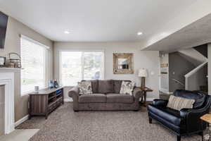 Living room featuring light colored carpet, baseboards, stairs, and recessed lighting
