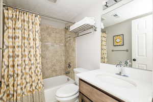 Full bath featuring toilet, vanity, and shower / tub combo