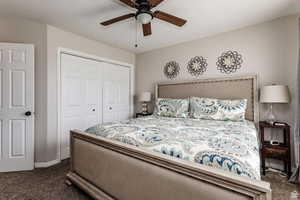 Bedroom with dark carpet, a closet, ceiling fan, and baseboards