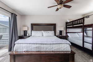 Carpeted bedroom featuring multiple windows and a ceiling fan