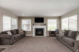 Living area with healthy amount of natural light, carpet floors, baseboards, a tiled fireplace, and recessed lighting