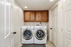 Washroom with washing machine and dryer, cabinet space, baseboards, recessed lighting, and a textured ceiling
