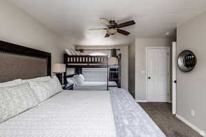 Carpeted bedroom featuring baseboards, a ceiling fan, and a textured ceiling