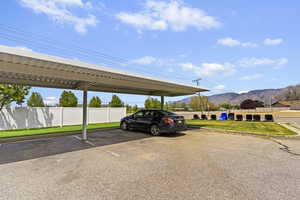 Covered parking lot featuring a mountain view and fence