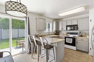 Kitchen with black microwave, electric stove, a sink, a peninsula, and decorative backsplash