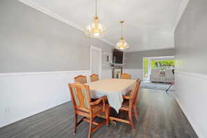 Dining room featuring a chandelier, ornamental molding, baseboards, and wood finished floors