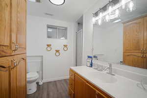 Full bath featuring toilet, wood finished floors, vanity, visible vents, and baseboards