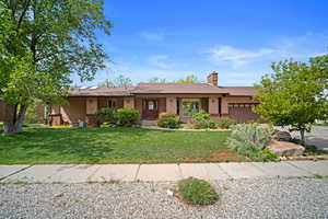 Single story home featuring stucco siding, an attached garage, a front lawn, and a chimney