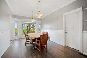 Dining area featuring baseboards, a chandelier, crown molding, and dark wood-style floors