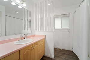 Full bathroom featuring baseboards, visible vents, wood finished floors, and vanity