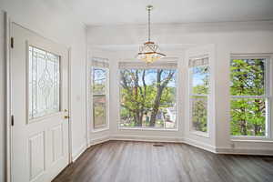 Foyer entrance with a chandelier, baseboards, visible vents, and dark wood-type flooring