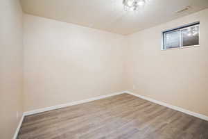 Spare room with baseboards, visible vents, a textured ceiling, and wood finished floors