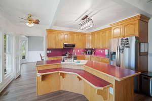Kitchen with an island with sink, a sink, stainless steel appliances, dark wood finished floors, and ceiling fan