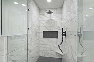 Primary oversized shower tiled to ceiling and glass shower door