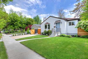 View of front of property featuring concrete driveway, a gate, a chimney, and a shingled roof