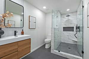Primary bathroom with oversized shower,  tiled to ceiling,  toilet, a double vanity, and recessed lighting
