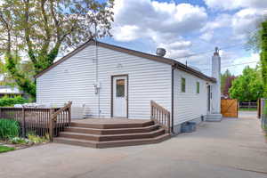 Back of house featuring entry steps to kitchen, a wood deck, & fence.