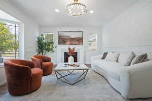 Living area with a chandelier, healthy amount of natural light, recessed lighting, a tiled fireplace, and moldings