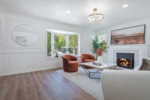 Living room featuring wood finished floors, a chandelier, a tile fireplace, baseboards, and recessed lighting