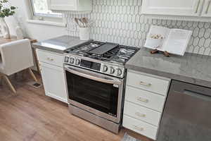 Kitchen featuring LG stainless steel appliances, backsplash, white cabinetry, and wood-style flooring