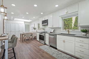 Kitchen with a sink, appliances with stainless steel finishes, backsplash, recessed lighting, and wood finished floors