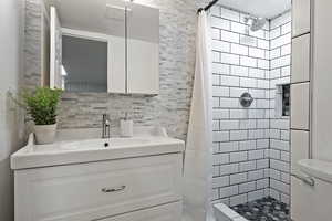 Bathroom with a shower stall, vanity, toilet, and tasteful backsplash