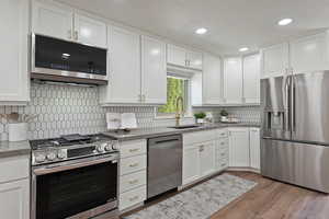 Kitchen featuring LG appliances with stainless steel finishes, a sink, white cabinets, decorative backsplash, and recessed lighting