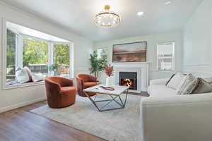 Living area featuring wood finished floors, a tiled fireplace, plenty of natural light, moldings, and a chandelier
