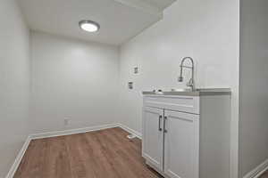 Laundry room featuring washer dryer hookup, wood-like floors, & cabinet space for possible kitchenette