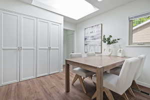 Dining area with a skylight, wood-type flooring, and baseboards
