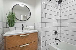 Bathroom featuring 5 foot tub with shower combination tiled to the ceiling , and single vanity