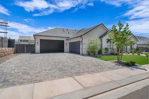 Ranch-style house featuring an attached garage, decorative driveway, and stucco siding