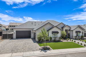 Ranch-style home featuring a garage, board and batten siding, decorative driveway, stone siding, and stucco siding