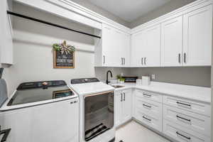 Laundry room with washing machine and clothes dryer, cabinet space, and light tile patterned floors