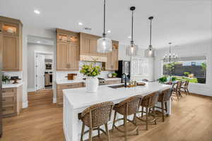 Kitchen with a sink, backsplash, light wood-style flooring, a kitchen breakfast bar, and recessed lighting