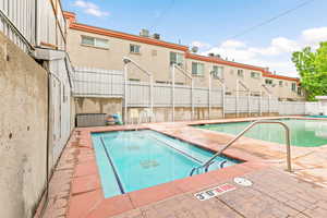 Community pool featuring fence and a jacuzzi