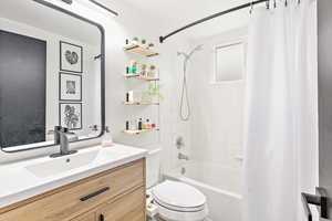 Bathroom with toilet, shower / bath combo, and vanity