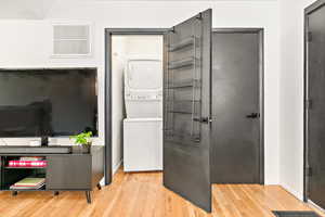 Washroom with stacked washer and clothes dryer,hardwood flooring, and baseboards