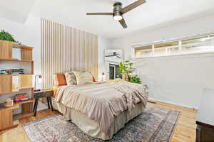 Bedroom featuring light hardwood floors, textured headboard, and a ceiling fan