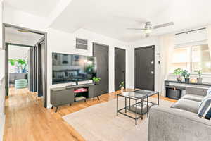 Living area featuring wood finished floors and ceiling fan and coat and laundry closets with hallway.