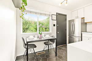 Kitchen with freestanding refrigerator, white cabinets, hexagon tiles and dining area