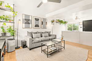 Living room with wood finished floors, ceiling fan, and kitchen island